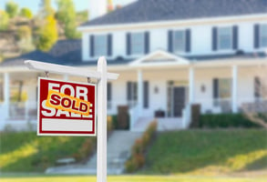 A white house has a sold sign in front of it.